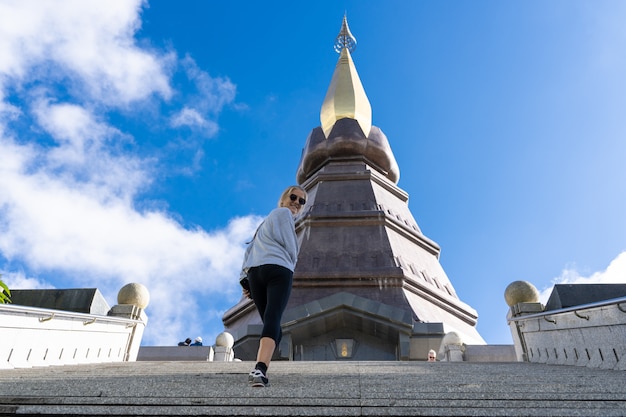 Chica con gafas de sol subiendo los escalones de una pagoda