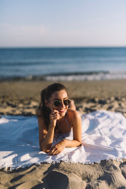 Chica con gafas de sol tomando el sol en la playa