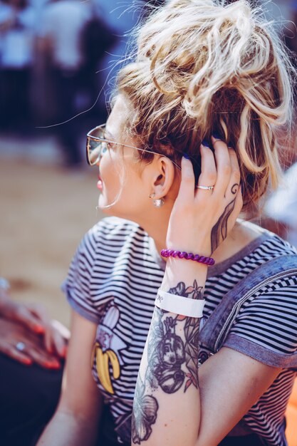 chica en gafas de sol vintage con tatuajes retrato de primer plano en la calle durante un picnic con amigos. Chica escalofriante