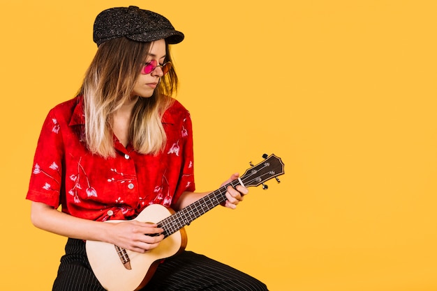 Foto gratuita chica con gafas tocando el ukelele