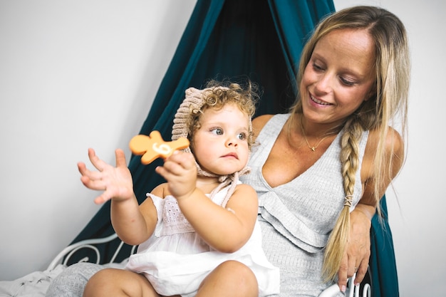 Chica con galleta en las rodillas de la madre