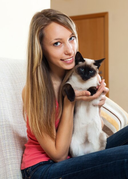 Chica con un gato siamés en la habitación