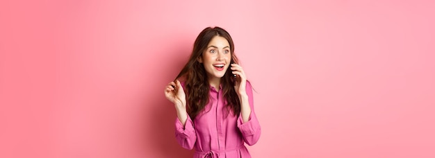 Foto gratuita chica glamurosa hablando por teléfono y jugando con el cabello luciendo feliz y relajada durante la conversación ca