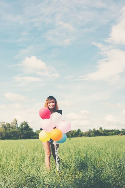 Chica con globos de colores en un campo