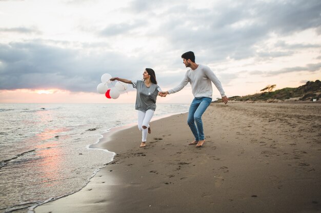 Chica con globos mientras su novio la agarra de la mano