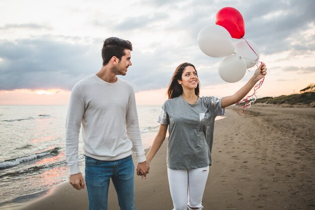 Chica con globos mientras su novio la agarra de la mano