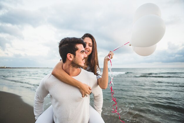 Chica con globos mientras su novio la lleva en su espalda