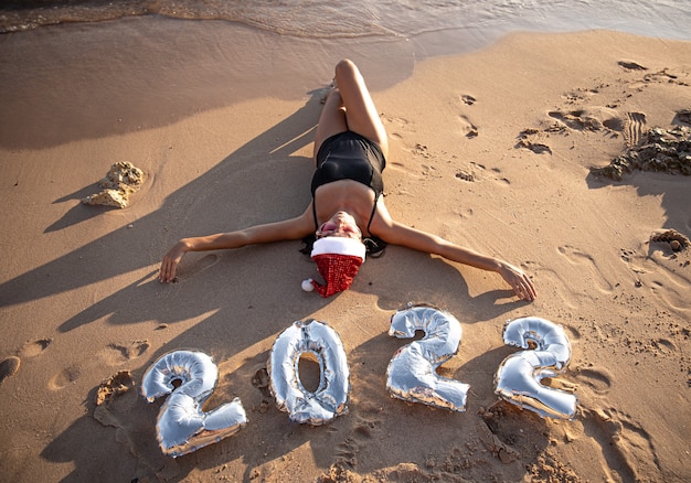 Foto gratuita chica con globos plateados en forma de números para el próximo año cerca del mar