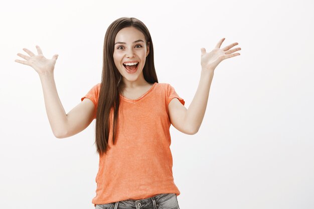 Chica guapa alegre y emocionada regocijándose, levantando las manos aliviado o agradecido, celebrando la victoria