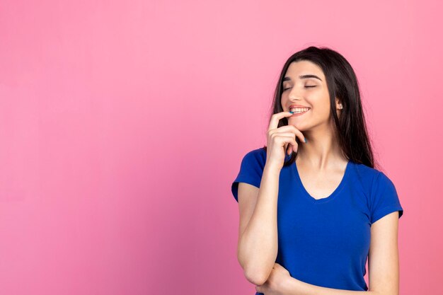 Chica guapa alegre mordiendo su uña y sonriendo