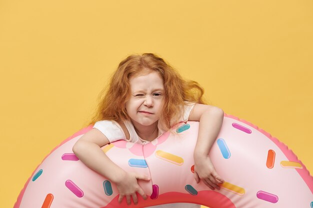 Chica guapa con cabello largo abrazando círculo inflable de natación y arrugas