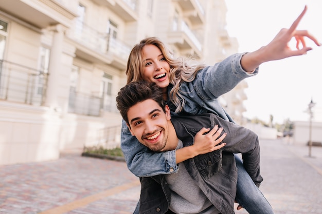 Chica guapa caucásica caminando por la ciudad con su novio. Hombre morena sonriente pasar el fin de semana con su novia.