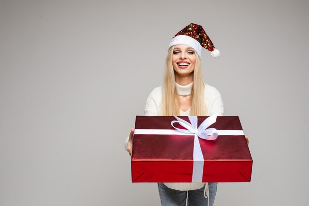 Chica guapa dando regalo de Navidad a la cámara.