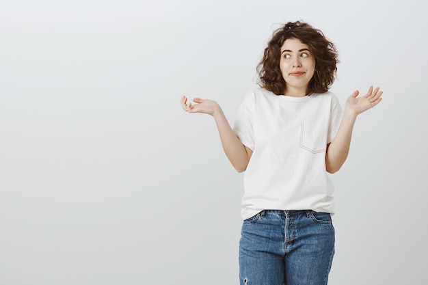 Chica guapa despistada encogiéndose de hombros con las manos extendidas hacia los lados, no sé nada, no tengo idea