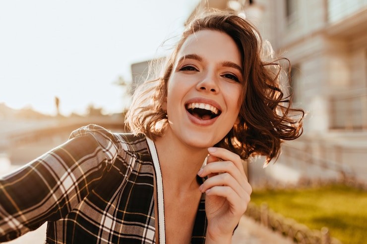 Foto gratuito chica guapa emocionada haciendo selfie. tiro al aire libre de escalofriante modelo femenino posando en la ciudad.