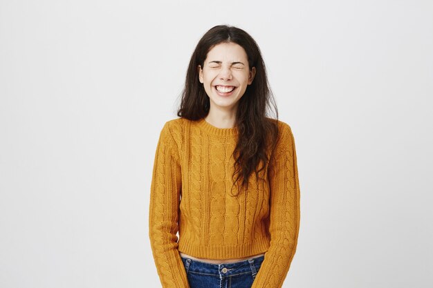 Chica guapa feliz y despreocupada riendo a carcajadas con los ojos cerrados, escucha una gran broma