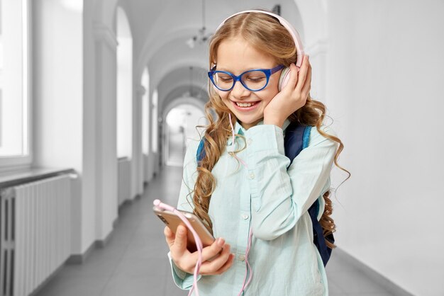 Chica guapa con gafas azules escuchando música con auriculares