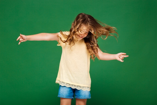 Foto gratuita chica guapa joven bailando sobre la pared verde