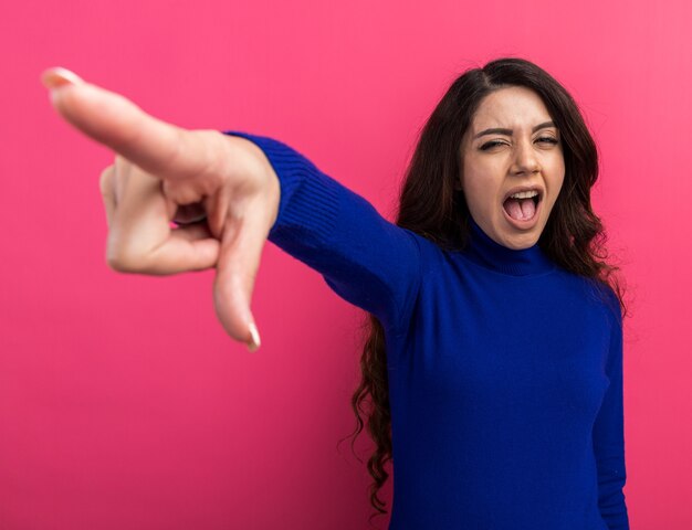 Chica guapa joven confiada mirando a la cámara apuntando al lado