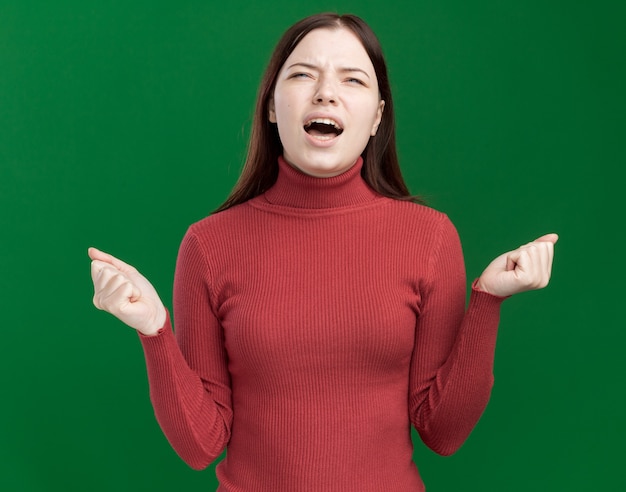 Chica guapa joven enojada mirando hacia arriba gritando con los puños cerrados