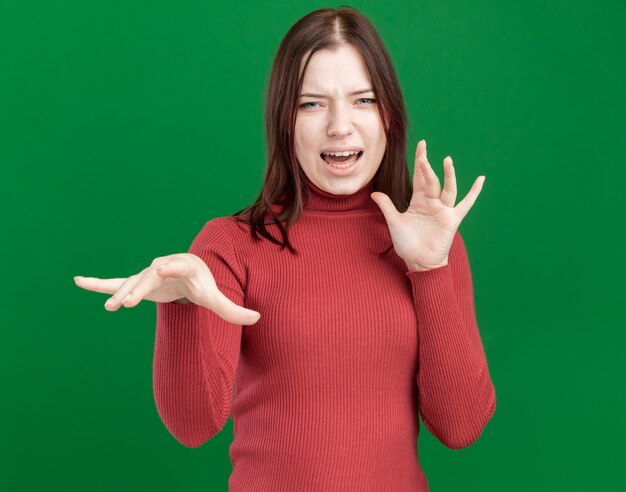 Chica guapa joven molesta estirando la mano manteniendo otra en el aire