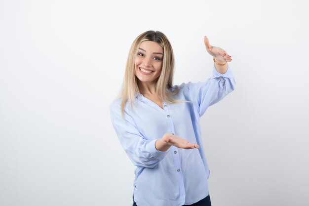 Chica guapa joven de pie y posando en blanco.