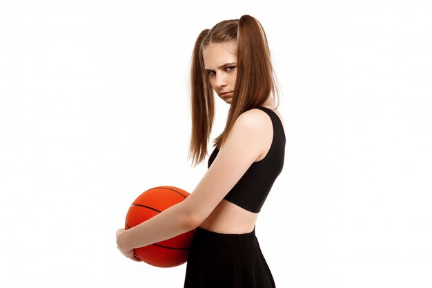 Chica guapa joven posando con baloncesto, aislado en la pared blanca