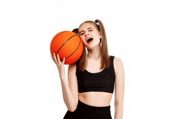 Chica guapa joven posando con baloncesto, aislado en la pared blanca