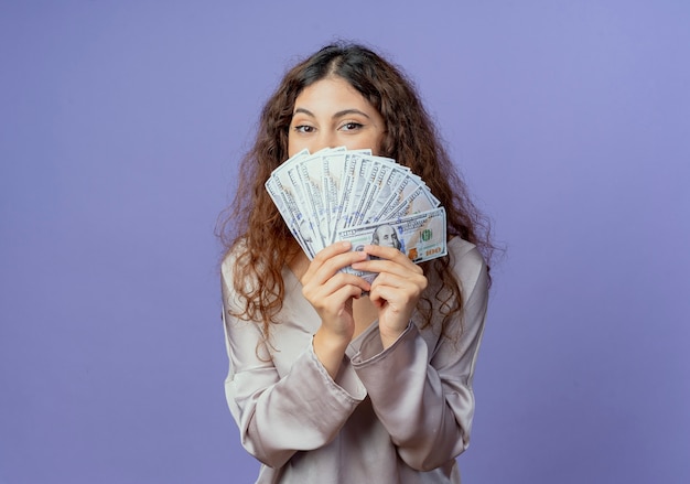 Foto gratuita chica guapa joven rostro cubierto con dinero aislado en la pared azul