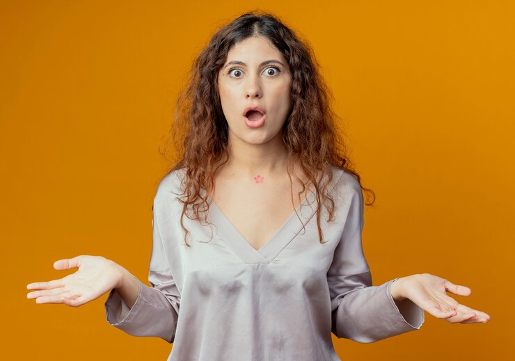 Foto gratuito chica guapa joven sorprendida extiende las manos aisladas en la pared amarilla