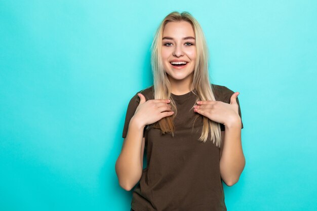 Chica guapa joven sorprendida que parece aislada en la pared azul