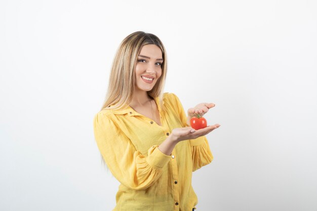 chica guapa mostrando tomate rojo sobre blanco.