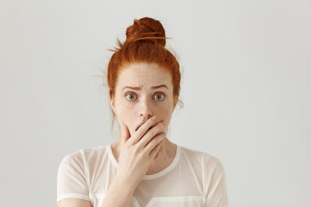 Chica guapa de ojos saltones asustada y conmocionada con cabello naranja habiendo sorprendido la expresión facial