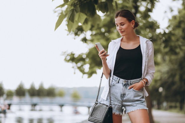 Chica guapa en el parque con teléfono