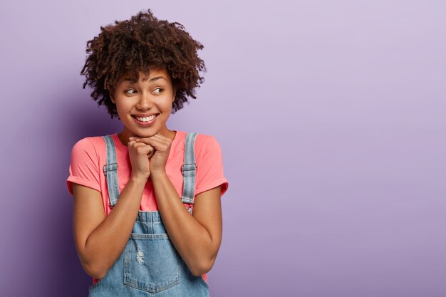 Chica guapa de pelo rizado mantiene las manos juntas