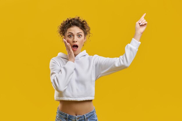 Chica guapa con el pelo rizado de pie sorprendida sorprendida