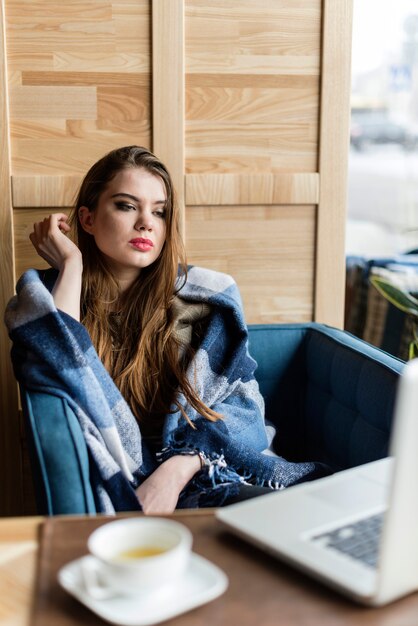 Chica guapa relajada con portátil en una cafetería