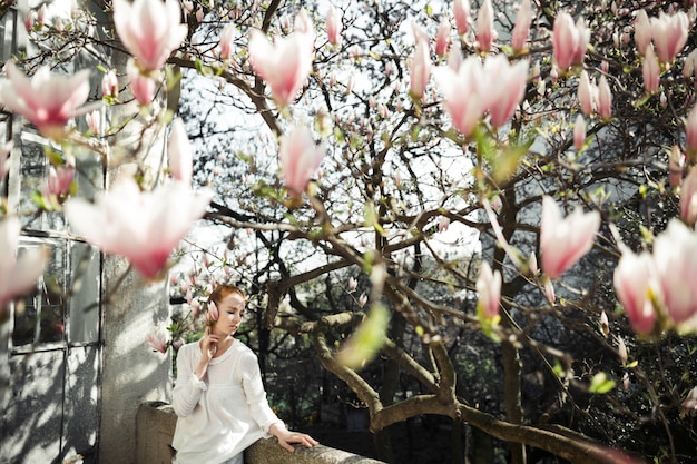 Chica guapa en una sesión de fotos de primavera con magnolia