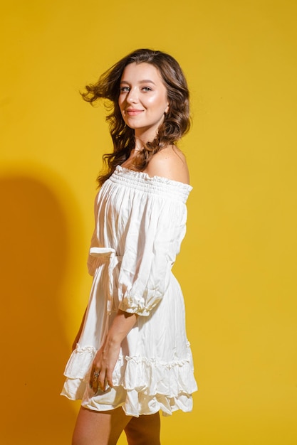 Chica guapa sonriente con el pelo rizado guiñando un ojo mostrando un gesto de paz con la lengua Sobre fondo amarillo