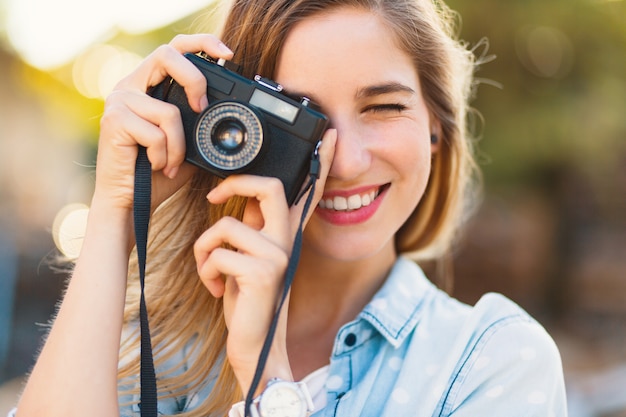 Chica guapa tomando fotos con una cámara vintage en un día soleado