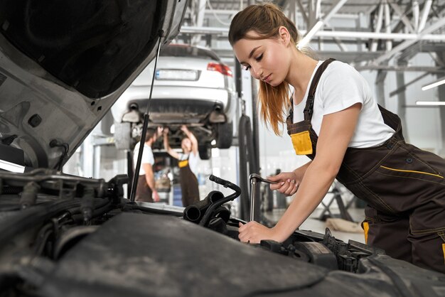 Chica guapa trabajando como mecánico en autoservicio.