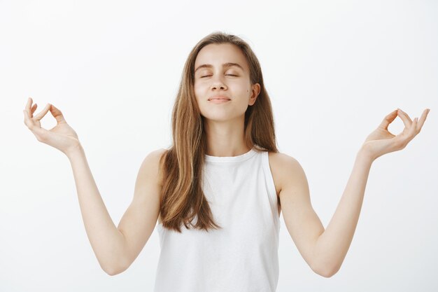 Chica guapa tranquila meditando, relajándose durante el yoga