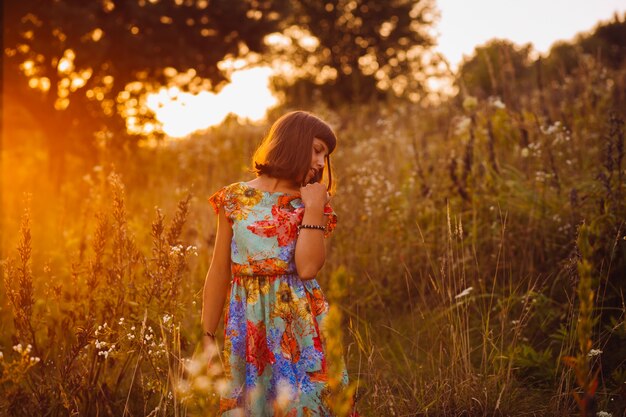 Chica guapa en un vestido brillante plantea en el campo