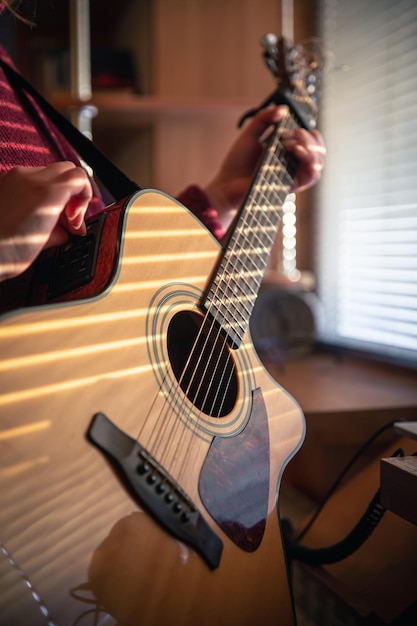 Chica con una guitarra en la luz del sol a través de las persianas.