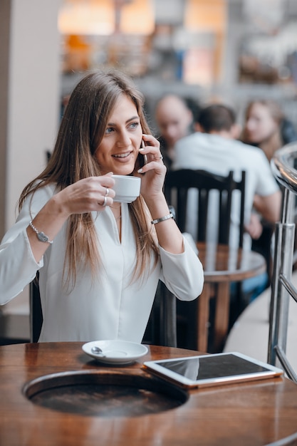 Chica hablando por teléfono mientras toma un café