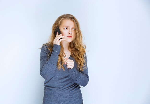 Chica hablando por teléfono y parece aterrorizada.