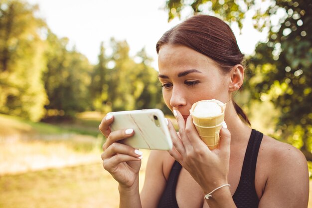 Chica haciendo ejercicio en el parque y tomando un helado