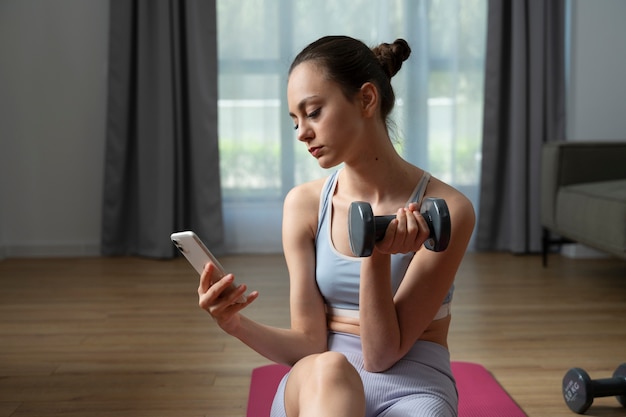 Chica haciendo ejercicio con un teléfono inteligente de tiro medio