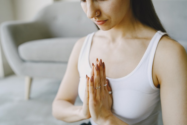 Foto gratuita chica haciendo ejercicios de yoga en casa cerca de un sofá y una ventana en ropa deportiva