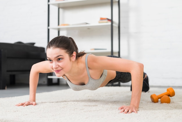 Foto gratuita chica haciendo flexiones en su casa